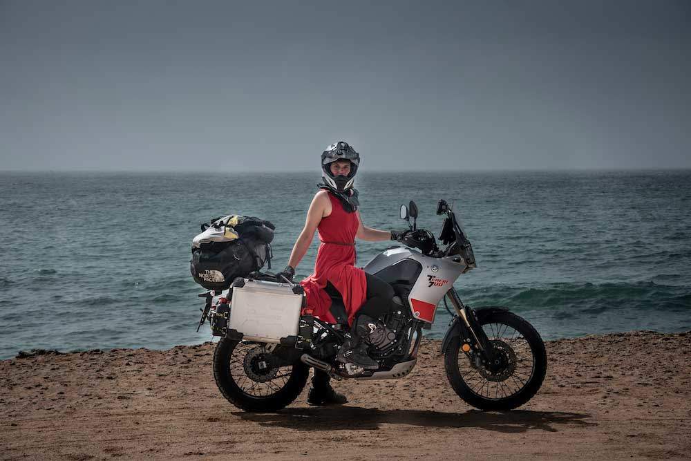 Lea Rieck mit dme Motorrad in der Western Sahara vor dem Meer.