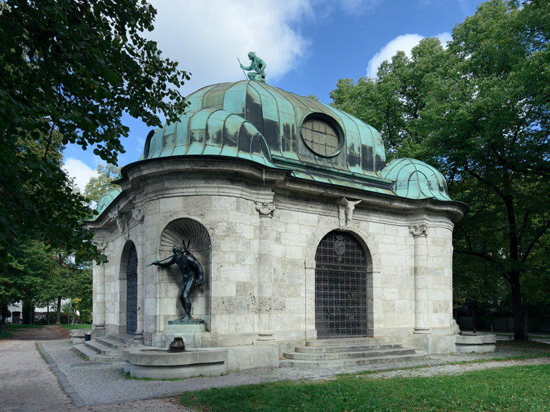 Gebäude mit einer bronzenen Skulptur in einer Nische und einer Skulptur auf dem Dach: Hubertsbrunnen in München von Adolf von Hildebrand.