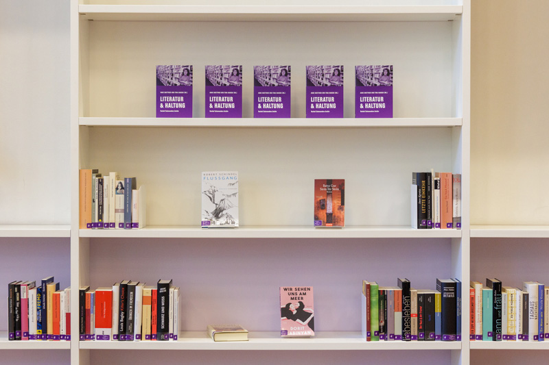 Blick auf ein repräsentatives Bücherregal, ganz zuoberst das Lesebuch zur Ausstellung «Literatur & Haltung»