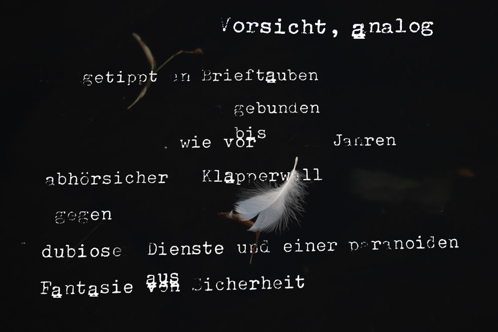 weiße Schrift auf schwarzem grund mit weißer Feder. „Vorsicht analog. getippt in Brieftauben gebunden bis wir vor Jahren abhörsischer Klapperwell gegen dubiose Dienste und einer paranoiden Fantasie aus von Sicherheit"