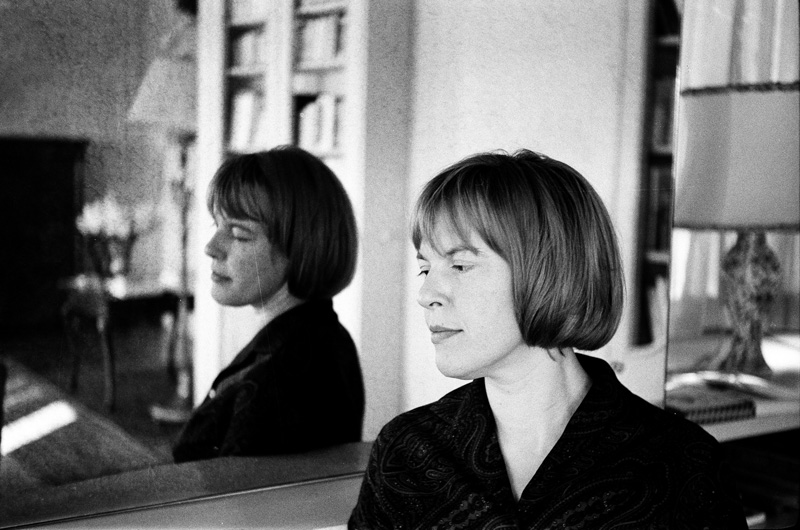 Frau im Halbprofil vor einem Spiegel stehend: Ingeborg Bachmann.