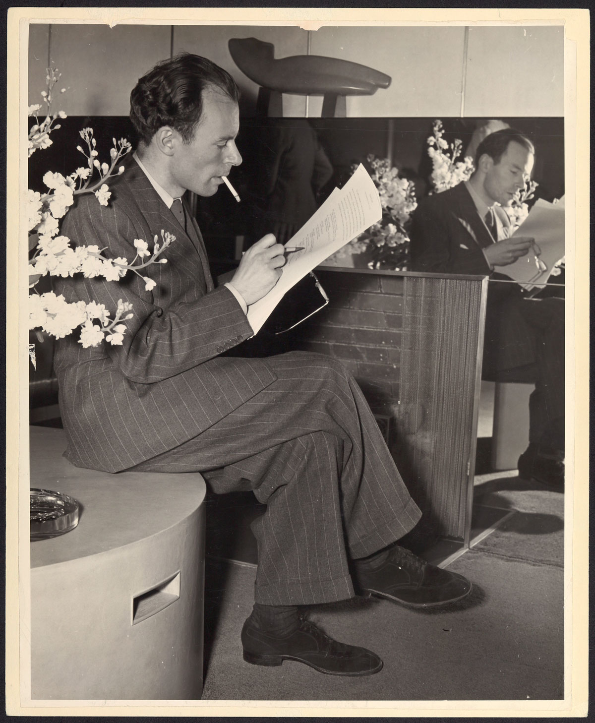 Klaus Mann schreibend und Zigarette rauchend im Foyer des Hotel Bedford, New York, um 1939.