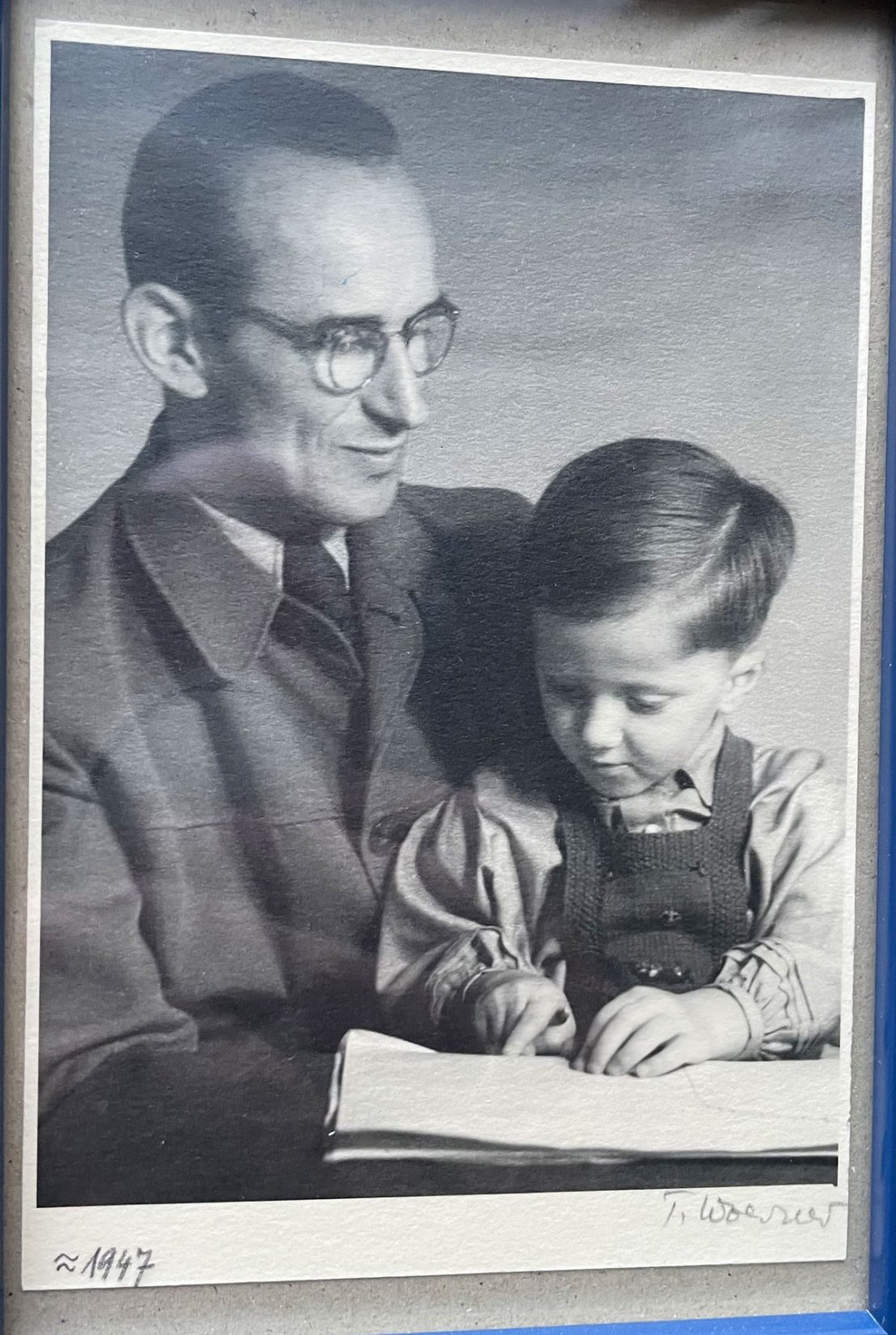 Vater hat Sohn auf dem Schoß, liest etwas. © privat
