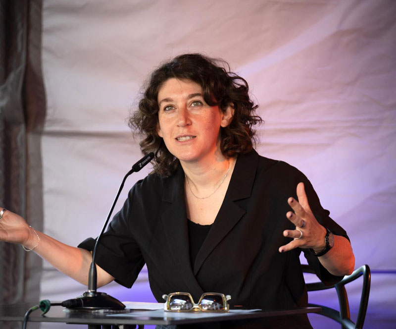 Frau auf dem Podium, gestikuliert und spricht: Lena Gorelik liest auf dem Sommerfest der Monacensia 2025. Junge jüdische Literatur