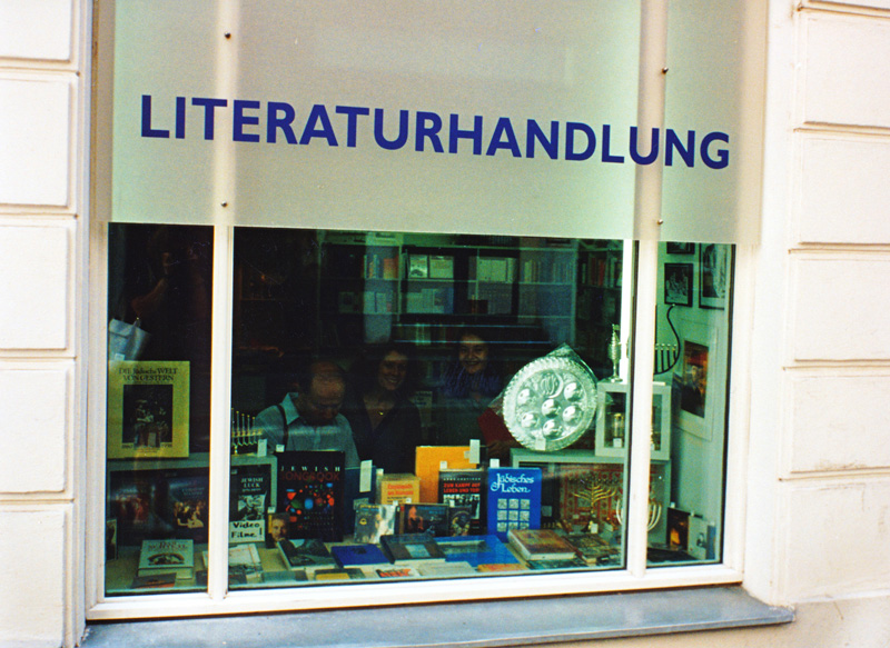 Blick auf das Schaufenster eines Buchladens, drei Personen befinden sich in der Literaturhandlung Berlin, darunter Rachel Salamander.
