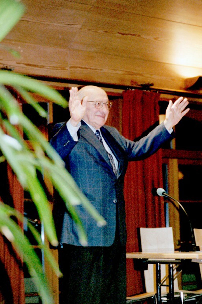 Ein Mann mit Brille, im Anzug und erhobenen Hände stehend: Marcel Reich-Ranicki auf dem Tarbut-Kulturkongress 2003.