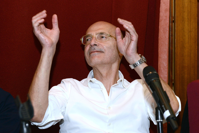 Mann mit Brille sitzend vor Mikrofon mit erhobenen Händen: Maxim Biller.