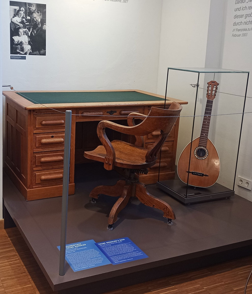 Schreibtisch mit Schreibtischstuhl und Guitarre von Frank Wedekind in der Ausstellung «Von der Bohème zum Exil» in der Monacensia, #LiterarischesMünchen