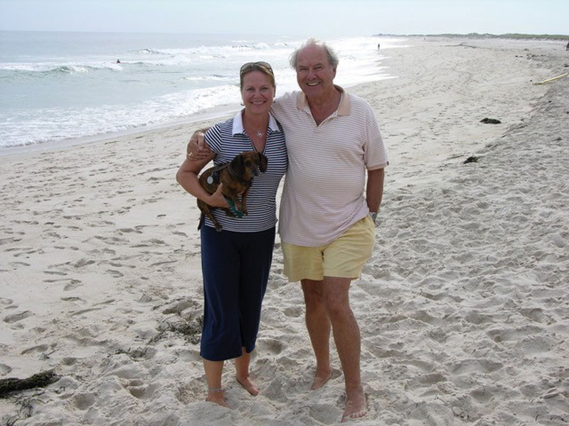 zwei Personen am Strand, mittelalte Frau mit Dackel im Arm, umarmt von weißhaarigen Mann: Sebastian Westermeier mit Tochter