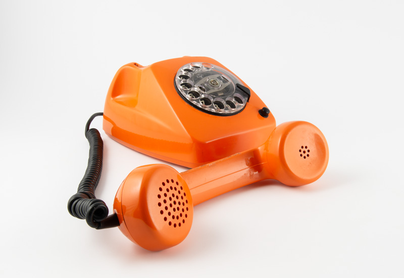 Orangenes Wählscheiben-Telefon mit abgelegten Hörer: Visual für die Sneak-Peak-Archivalienschau der Monacensia in 2026.