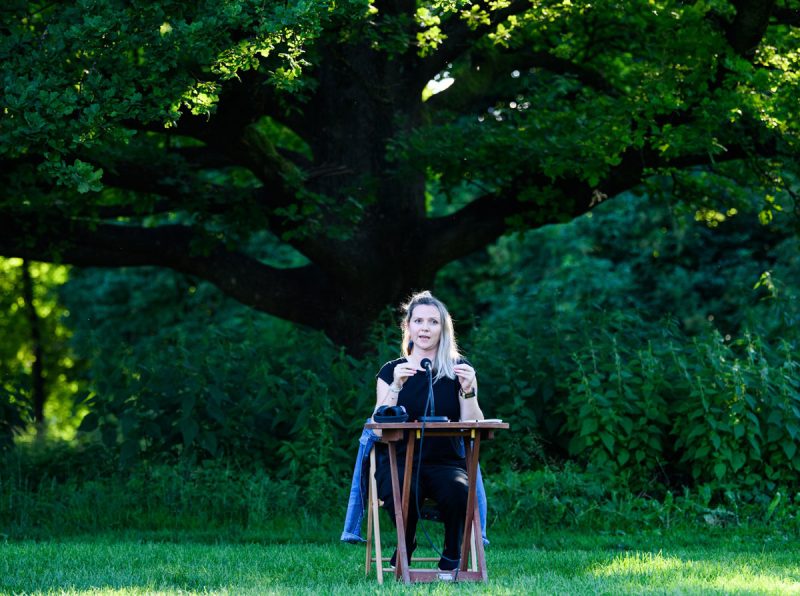 Volha Hapeyeva im grünem an einem Tisch mit Mikrofon sitzend.