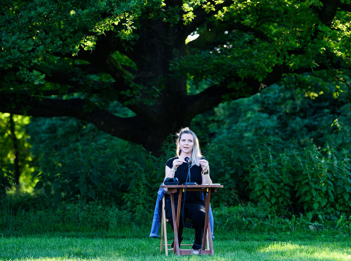 Volha Hapeyeva im grünem an einem Tisch mit Mikrofon sitzend.