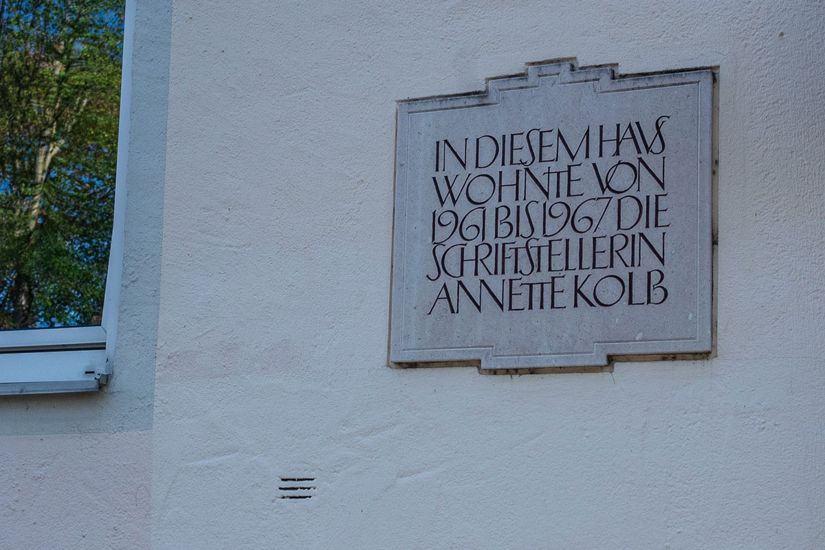 Beschriftung an Gebäude mit Aufschrift: in diesem Haus wohnt von 1961 bis 1967 die Schriftstellerin Annette Kolb.