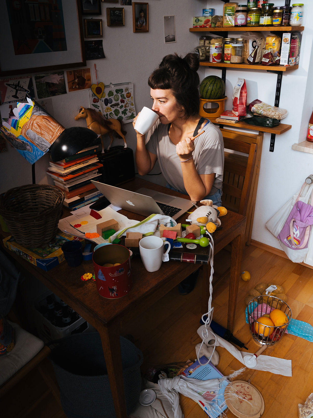 Frau Kaffee trinkend am Schreibtisch mit Büchern, Laptop und in Küche