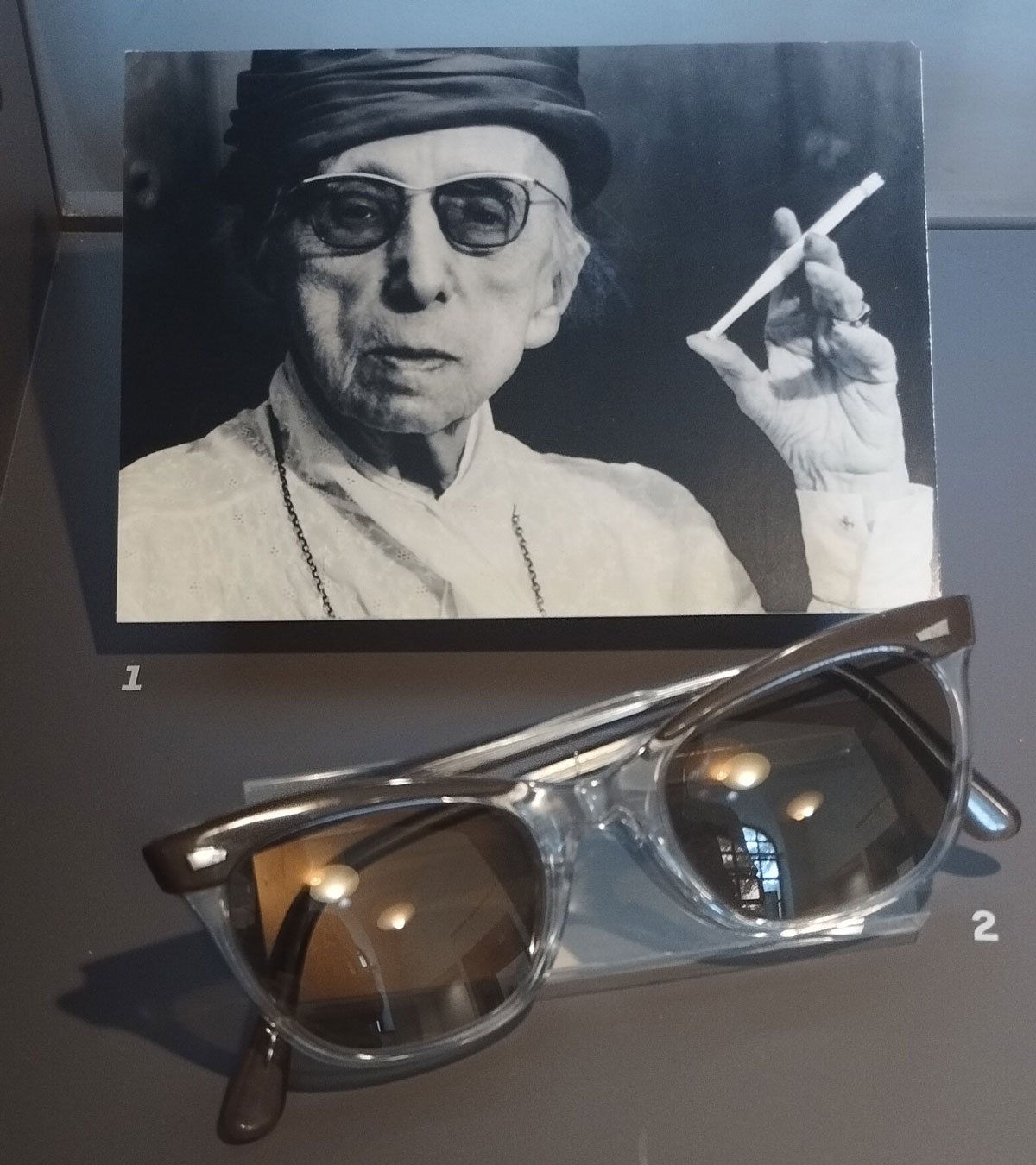 Foto von Annette Kolb mit Brille und Zigarette, Vitrine, dafür zusammengeklappte Brille von ihr, ausgestellt in "literarisches München zur Zeit von Thomas Mann", #literarischesMünchen