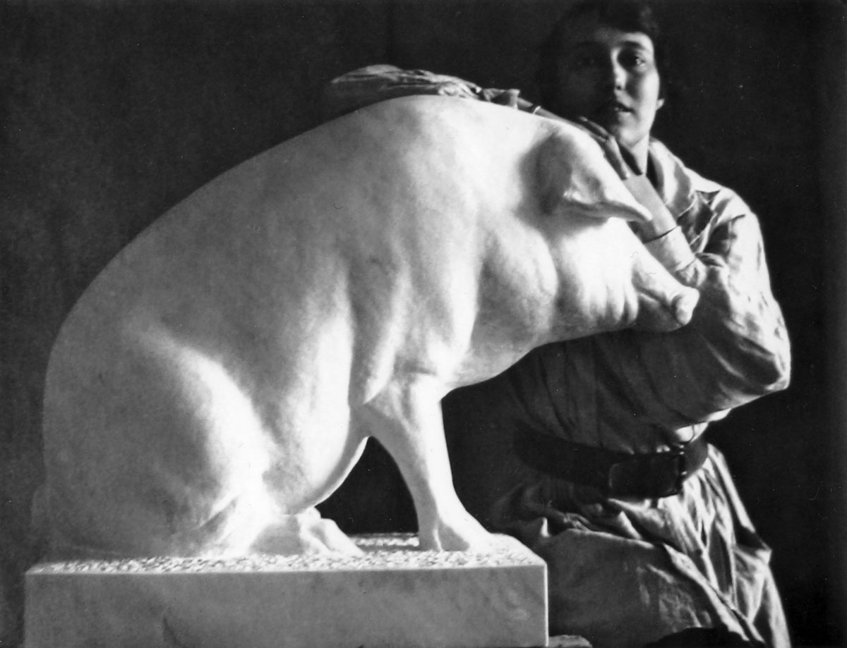 Frau hinter einem skulptierten Schwein, Hände auf den Kopf des Schweines aufgestütz: Christa Winsloe.