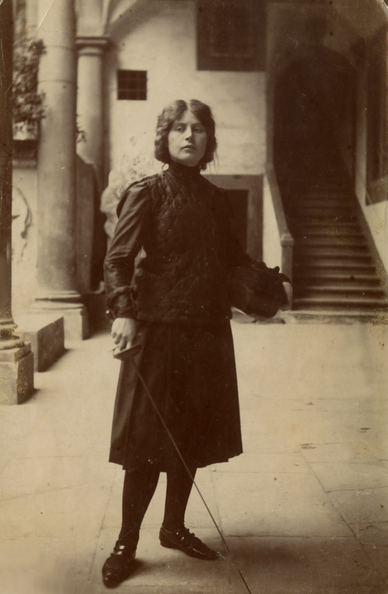 Elisabeth von Hildebrand in der Loggia von San Francesco di Paola in Florenz in Fechterkostüm mit Degen in der Hand und untergeklemmten Helm.