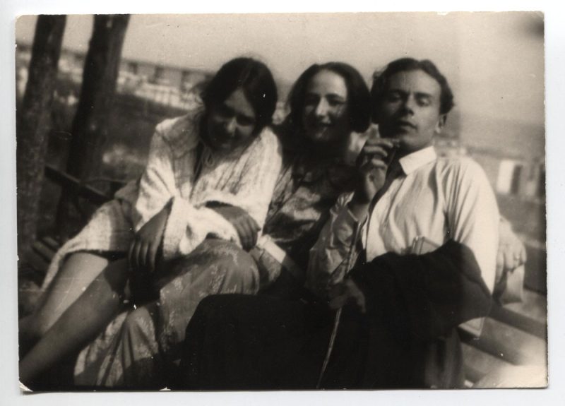 Historische Schwarz-Weiß-Fotografie im Sommer 1924. Drei Personen sitzend lächelnd in die Kamera blickend: Erika Mann, Pamela Wedekind und Klaus Mann.