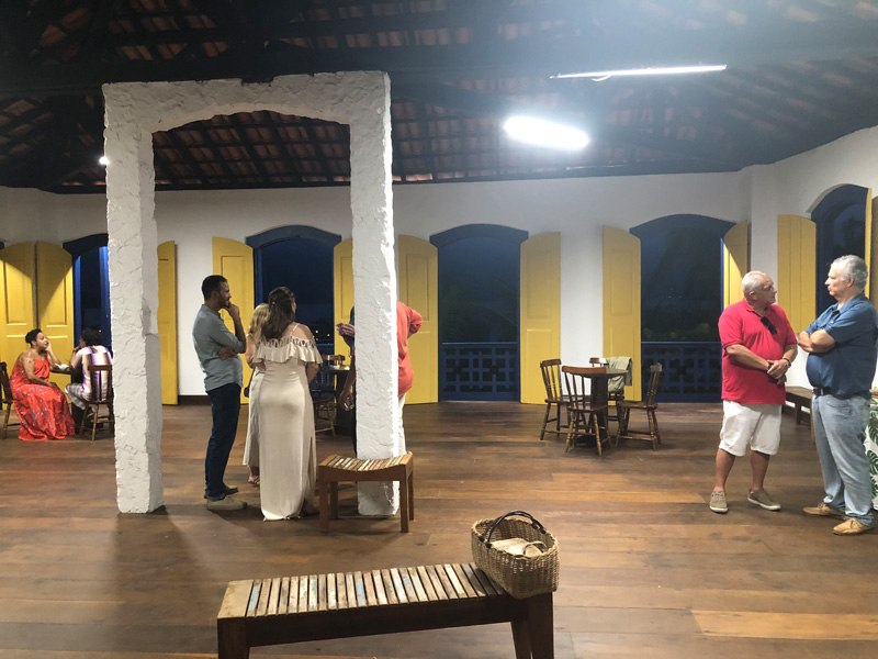 Innenansicht eines Hauses mit festlich und sommerliche gekleideten Menschen: Julia Manns Kindheitshaus in Paraty, Brasilien