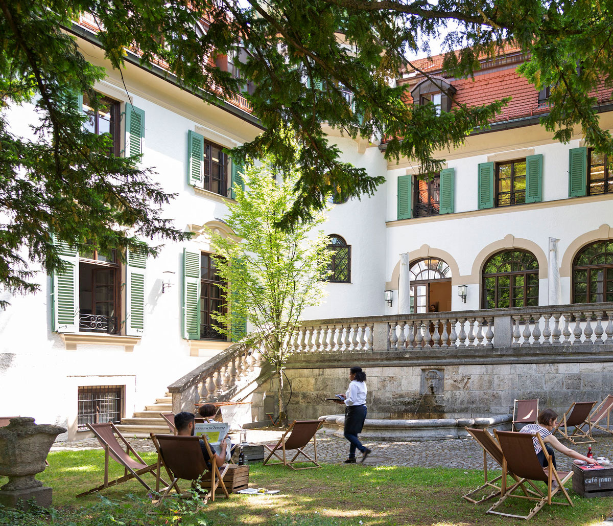 Menschen auf Liegestühlen im Lesegarten der Monacensia