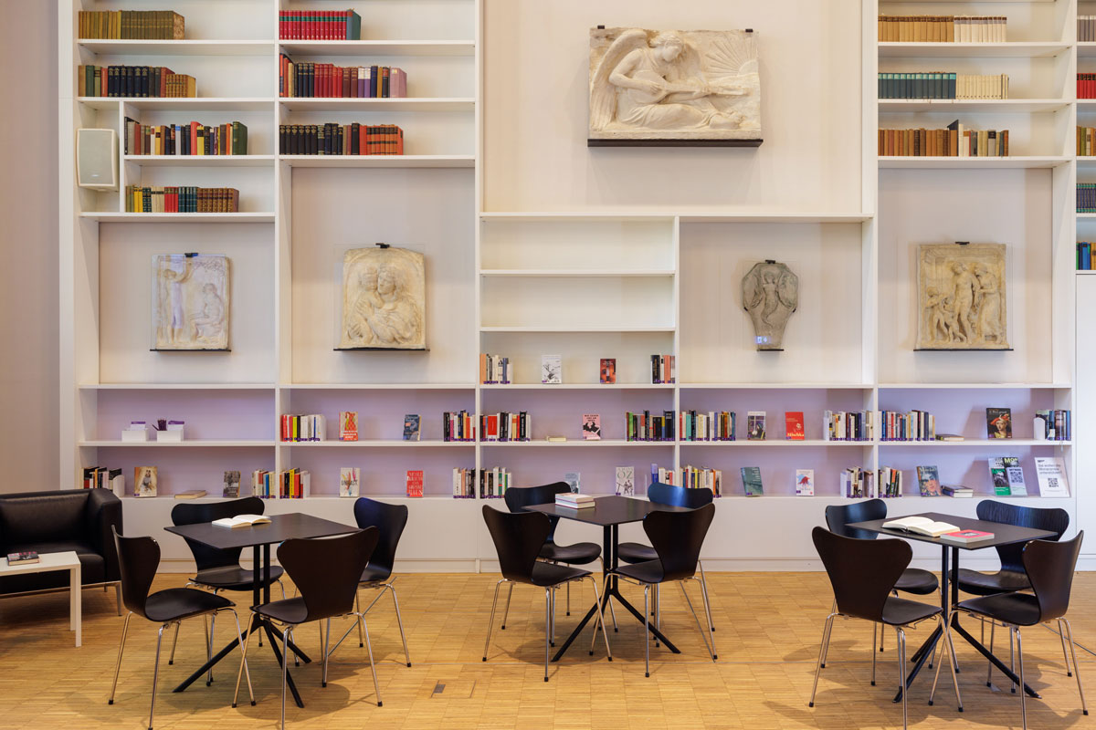 Blick auf eine historische Bücherwand im Forum Atelier der Monacensia, mit Reliefs von Adolf von Hildebrands.