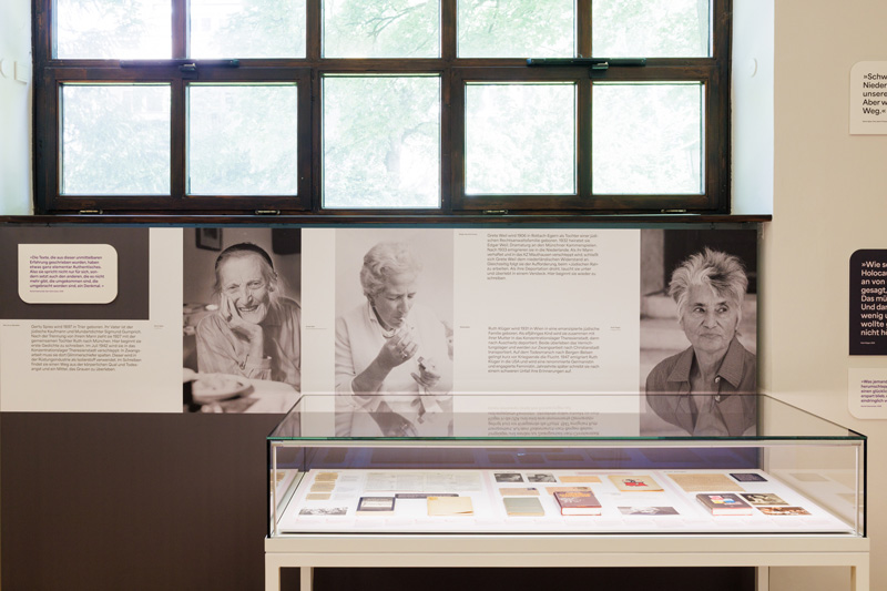 Blick in die Ausstellung von Literatur & Haltung v.l.n.r. an der Wand: Gerty Spies, Grete Weil, Ruth Klüger, dazwischen Texte und davor Vitrine mit Büchern und Dokumenten.
