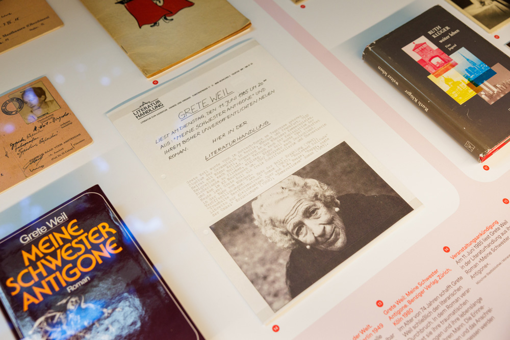 Blick in die Vitrine mit Ausschnitt zu Grete Weil: Bücher, Pass, Dokumente, Veranstaltungsankündigung zu einer Lesung. Literatur & Haltung, Monacensia.