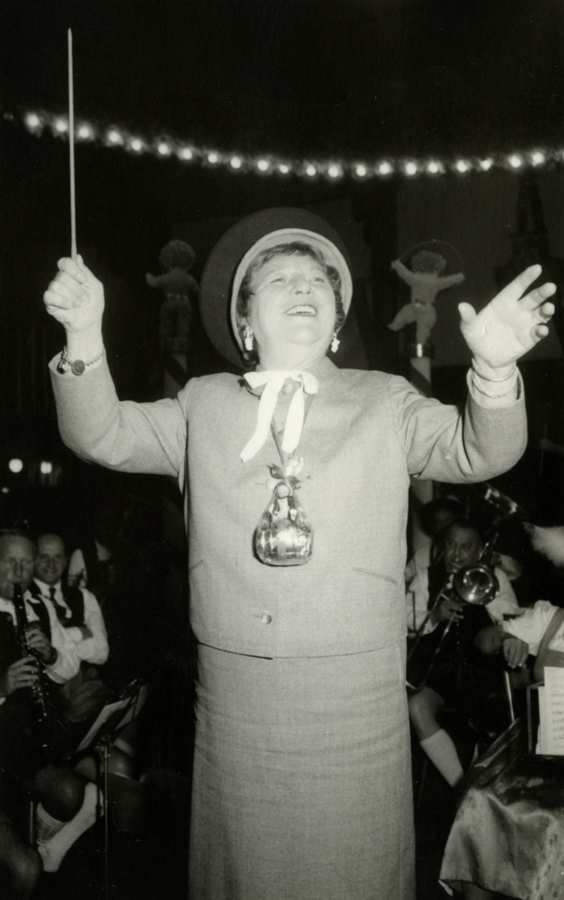 Eine Frau, lachend mit einem erhobenen Dirigentenstab in der hand: Liesl Karlstadt auf dem Oktoberfest.
