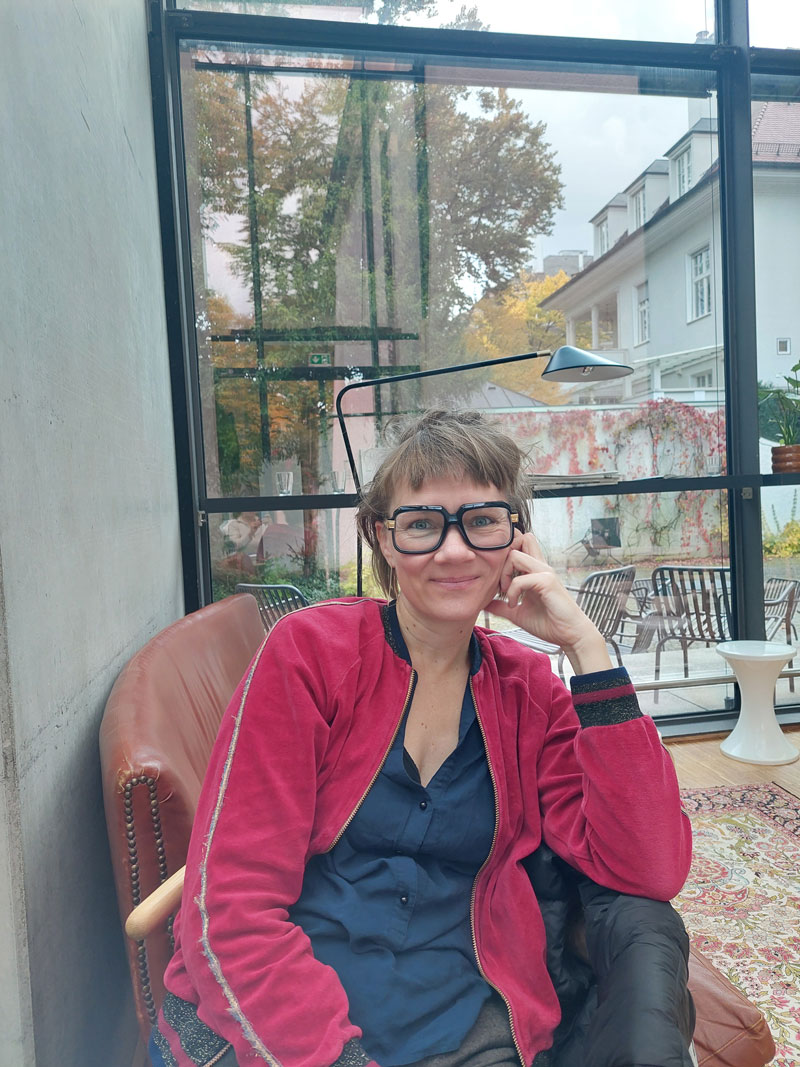 Raphaela Bardutzky auf Stuhl sitzend im Café Lev in der Monacensia, anlässlich Interview zur #AtelierMonaco-Szene mit Christina Madenach