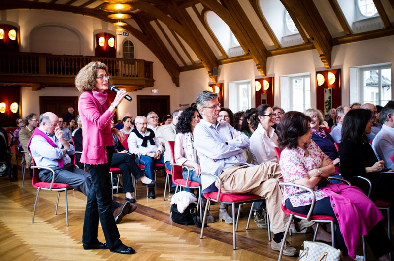 Frau in pinker Jacke mit Mikrophon in der Hand vor sitzendem Publikum: Rachel Salamander bei Tarbut 2018 auf Schloss Elmau