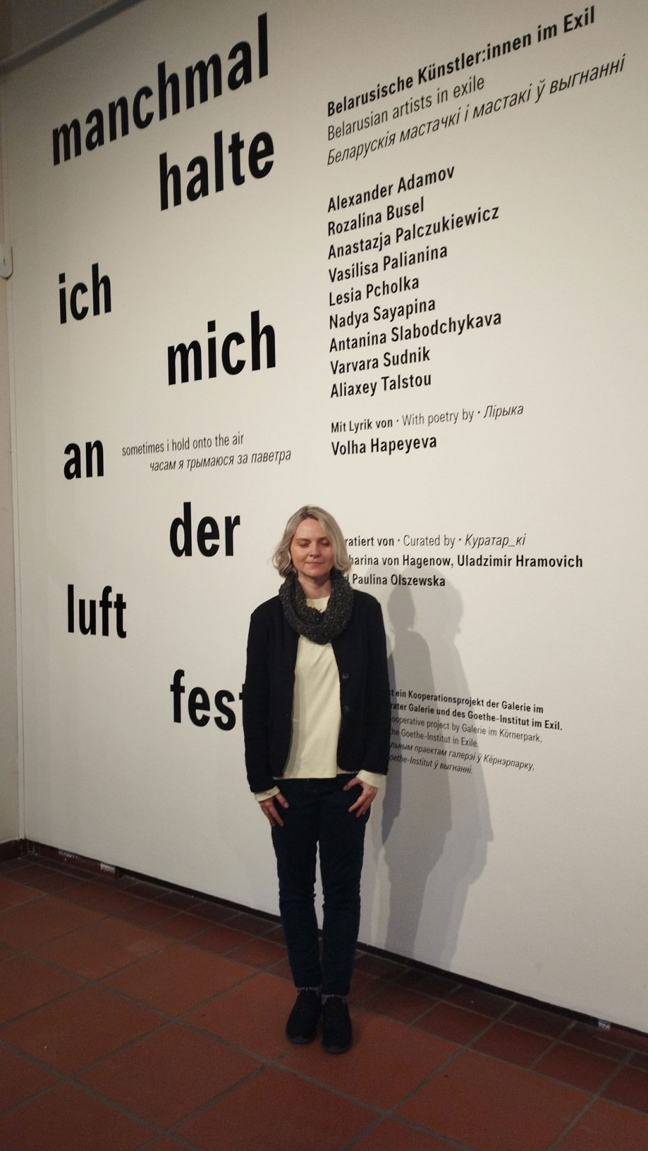 Volha Hapeyeva vor einer Wand mit Wörtern stehend, bei der auch Hinweis auf die Lyrik von ihr ist mit Überschrift Belarusische Künstler:innen im Exil