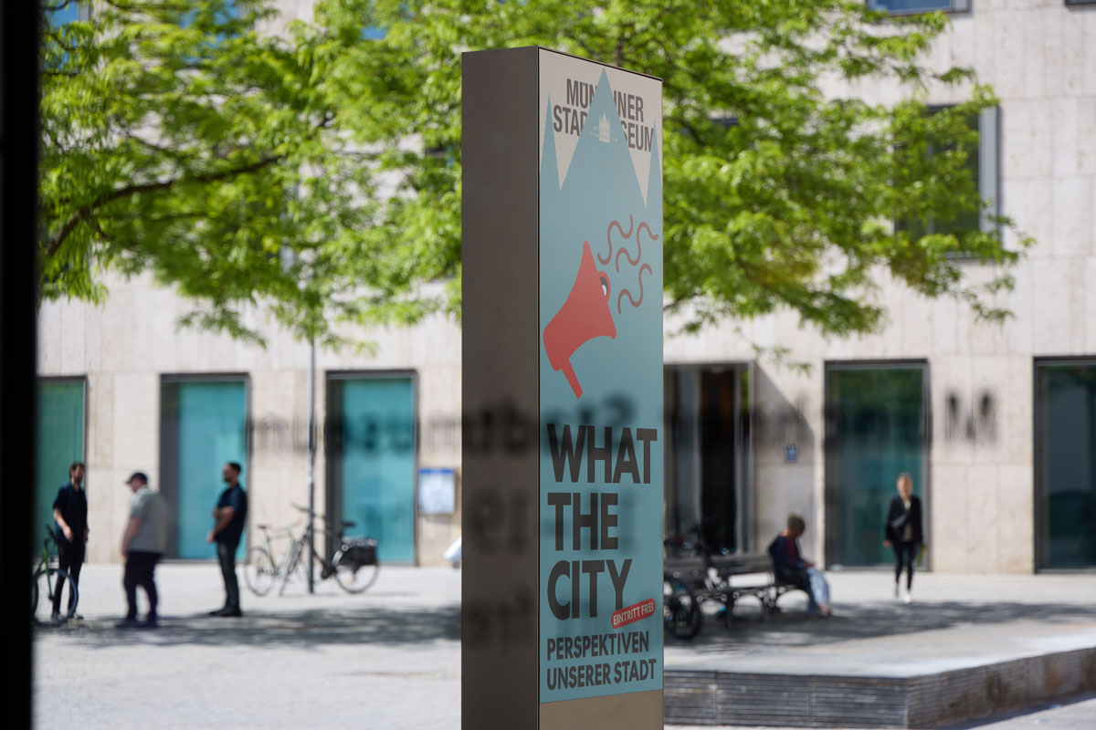 Stelle mit Ausstellungshinweis auf What the City des Münchner Stadtmuseums.